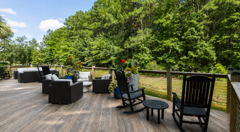 A deck with chairs and tables on it with trees in the background at Parker Point apartments for rent in Charleston. 